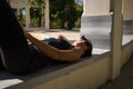Young woman, brunette, slender, dressed in black and wearing sunglasses, lying on a bench receiving the sun's rays relaxed. Royalty Free Stock Photo