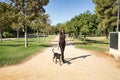 Young woman, brunette, slender, dressed in black and wearing sunglasses, walking her dog in a park. Concept beauty, fashion,
