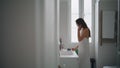 Young woman brushing hair in bathroom. Tender girl applying mask after shower Royalty Free Stock Photo