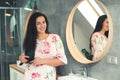 Young woman brushing healthy long hair at bathroom. Brunette girl looking at camera and smiling. Long healthy and shiny hair Royalty Free Stock Photo