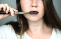 Young woman brushing her teeth with a black tooth paste with active charcoal, and black tooth brush on white background for Teeth Royalty Free Stock Photo