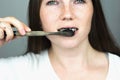 Young woman brushing her teeth with a black tooth paste with active charcoal, and black tooth brush on white background for Teeth Royalty Free Stock Photo