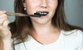 Young woman brushing her teeth with a black tooth paste with active charcoal, and black tooth brush on white background for Teeth Royalty Free Stock Photo