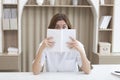 Young woman with bugged eyes covered her face with book Royalty Free Stock Photo