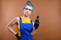 young woman builder in glasses stands in her hands in a screwdriver, a construction tool, a studio portrait copy space
