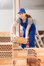Young woman builder stacking bricks in building site