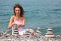 Young woman builds stone stacks on pebble beach Royalty Free Stock Photo