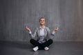 Young woman in business suit sitting in Lotus pose, restore energy, meditate. Health and work
