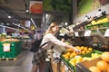 Young woman buys fruit in a supermarket. Girl is collecting oranges in a package during a supermarket shopping Royalty Free Stock Photo