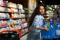 A young woman buys pallets of water in a supermarket. He takes it in his hands, packs it in a cart. Panic during a