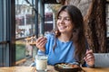 A young woman in a cafe dines on traditional shakshuka and ayran.