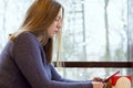 Young woman at cafe drinking coffee and using smartphone and wifi, connects to friends, downloads app or application from internet