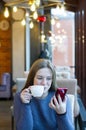 Young woman at cafe drinking coffee and using smartphone and wifi, connects to friends, downloads app or application from internet