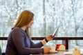 Young woman at cafe drinking coffee and using smartphone and wifi, connects to friends, downloads app or application from internet