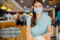 Young woman in cafe public place wearing the protective face mask.Mandatory mask wearing.Safety measures following in the indoor