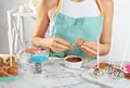 Young woman with cake pop and chocolate frosting at white marble table