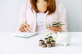 Young woman calculating expenses with stack of coins and piggy bank, Saving money for future investment concept Royalty Free Stock Photo