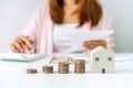 Young woman calculating home expenses with stack of coins, Saving money for property investment concept Royalty Free Stock Photo