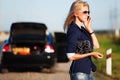 Fashion woman in sunglasses calling on mobile phone next to broken car Royalty Free Stock Photo