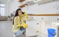 Young woman calling plumbing service as pipe under her sink in the kitchen is leaking Royalty Free Stock Photo