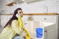 Young woman calls the plumber as she has water leaking from her kitchen sink pipe Royalty Free Stock Photo