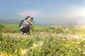 Young woman with a camera in a meadow taking nature photos at day time. Nature traveller against a blue sky with empty copy space Royalty Free Stock Photo
