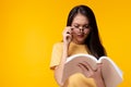 Young woman can not read book because her eyesight`s getting worse. Young Asian girl wears eyeglasses and holding text book. She i