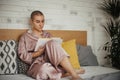 Young woman with cancer reading book, cancer awareness concept. Female cancer patient lying in bed, relaxing at home. Royalty Free Stock Photo