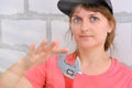 A young woman in a cap holding a large adjustable wrench. Plumber repairs and holds a red wrench