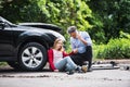 Young woman by the car after an accident and a man making a phone call. Royalty Free Stock Photo