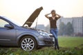 Young woman and a car with popped hood. Transportation, vehicles problems and breakdowns concept