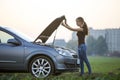 Young woman and a car with popped hood. Transportation, vehicles problems and breakdowns concept