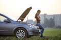 Young woman and a car with popped hood. Transportation, vehicles problems and breakdowns concept