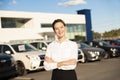 Young woman car rental in front of garage with cars on the background Royalty Free Stock Photo