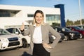 Young woman car rental in front of garage with cars on the background Royalty Free Stock Photo