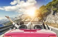 Young woman in a car on the road to the sea against a backdrop of beautiful mountains on a sunny day.