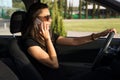 A young woman in the car talks on the smart phone and drives