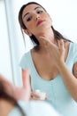 Young woman caring of her skin standing near mirror in the bathroom. Royalty Free Stock Photo