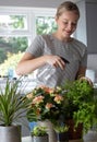 Young Woman Caring For And Watering House Plants With Spray