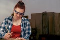 young woman carpenter smiling, designing furniture in her carpentry shop.