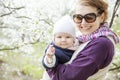 Young woman carrying her baby daughter outdoors in spring park Royalty Free Stock Photo