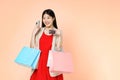 Young woman carrying shopping bags with using credit card and mobile phone standing over isolated on pink background Royalty Free Stock Photo