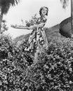 Young woman carrying a tray of Flowers in a garden