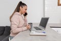 Smiling woman talking on smartphone while shopping online with a cup of coffee in her hand Royalty Free Stock Photo