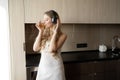 A young woman in casual clothes is relaxing with music in headphones in a cozy home, enjoying the morning sun from the