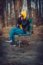 Young woman in casual clothes sitting on bench and photographing on old photo camera in forest. Female resting and Royalty Free Stock Photo