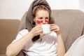 Young woman with casual clothes, towel on head and eye patches drinking hot tea and resting. Relax after taking shower