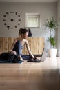 Young woman in casual clothing sitting on a mat in domestic living room using a laptop computer Royalty Free Stock Photo