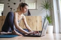 Young woman sitting on a mat on living room floor working or studying using a laptop Royalty Free Stock Photo