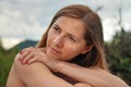 Young woman casual portrait - leaning on her palm and shoulder looking to side, closeup detail, blurred trees background